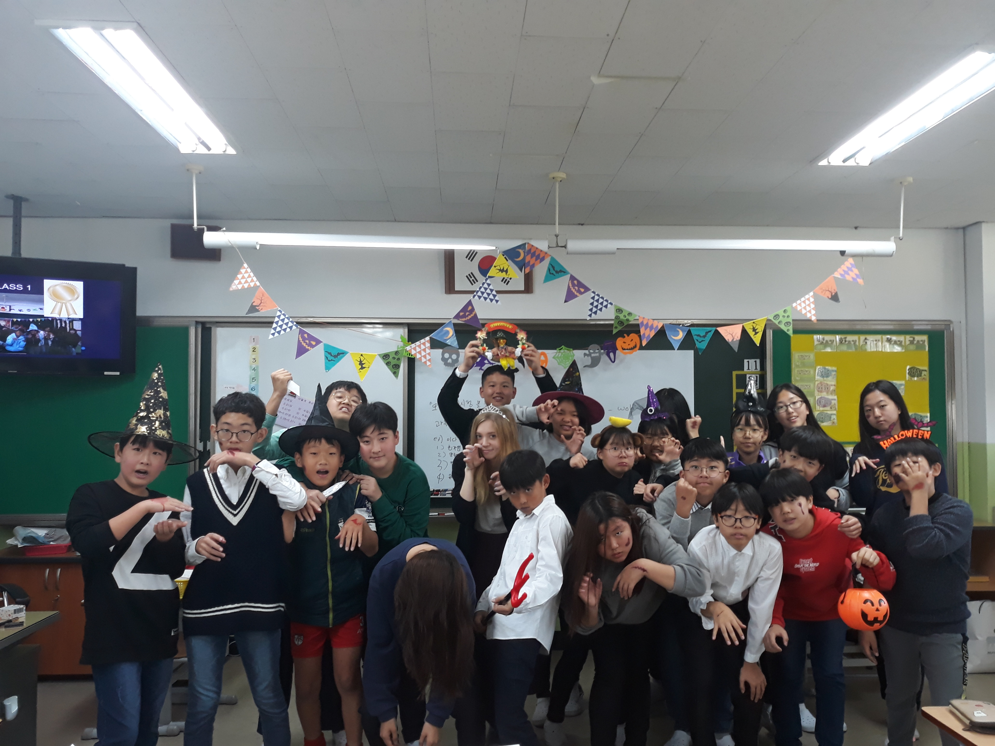 Melissa has a B.A. Linguistics and Asian Studies, TESOL Certificate ‘19. She is standing with her Korean students surrounding her inside a classroom. Everyone is wearing a Halloween costume.
